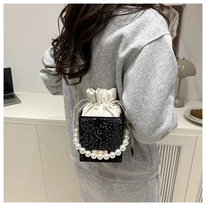 Detail of a black snake-embossed square bag with pearl handle and metal chain strap