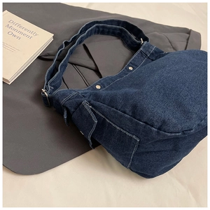 Détail du sac cabas en denim bleu foncé avec surpiqûres et poche latérale à rabat