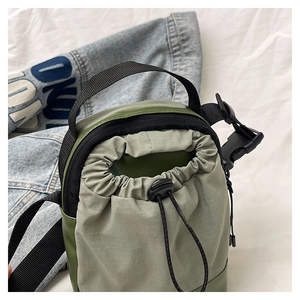 Detail of army green nylon crossbody bag with drawstring closure and plastic buckle