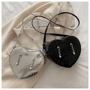 Detail of heart-shaped crossbody bags featuring crocodile texture and metal chain charms