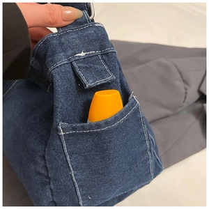 Détail du sac à bandoulière en jean bleu avec poche latérale et surpiqûres blanches