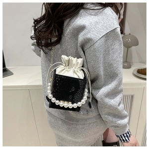 Detail of contrast drawstring bucket bag with pearl handle and snake pattern leather base