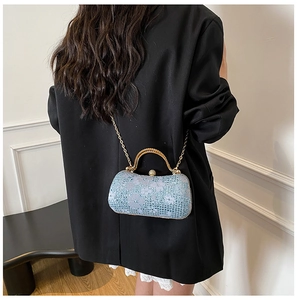 Détail du sac de soirée à paillettes avec poignée dorée sur un mannequin en tailleur