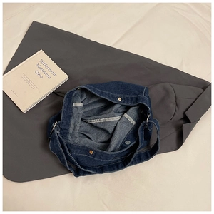 Detail of dark blue denim tote bag with metal magnetic snap closure and white stitching