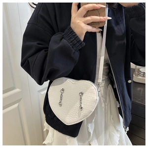 Detail of white heart-shaped crossbody bag with crocodile texture and silver chain