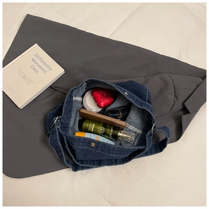 Détail de l'intérieur du grand sac en denim bleu foncé avec divers articles de cosmétique