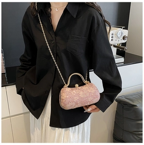 Détail de la pochette de soirée rose à paillettes avec anse dorée sur un mannequin