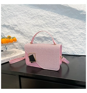Detailed shot of pink glitter crossbody bag with gold-tone buckle on dark wooden surface