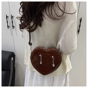 Brown crocodile heart bag with silver chain worn as a crossbody shoulder bag