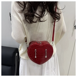 Model wearing a red heart-shaped crocodile pattern crossbody bag with silver chains