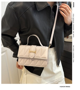 Détail du sac à bandoulière matelassé crème avec boucle dorée sur un mannequin