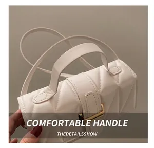 Détail d'un sac bandoulière matelassé blanc cassé avec boucle dorée sur un blazer