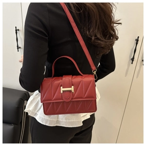 Détail du sac bandoulière en cuir matelassé rouge avec fermoir H doré porté par le mannequin