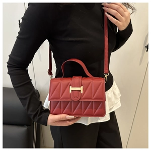 Detailed view of red quilted bag with a gold H-clasp and adjustable shoulder strap