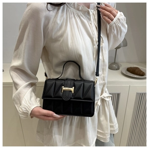 Close-up of black quilted handbag with golden H-clasp and leather shoulder strap