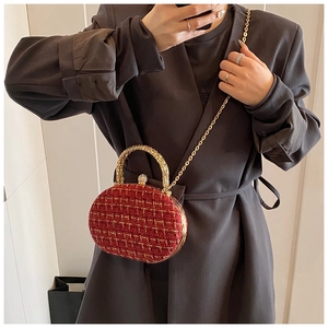 Close-up of red and gold tweed evening bag with metal handle and sparkling clasp