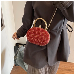 Dettaglio borsa da sera in tweed rosso con manico dorato e chiusura gioiello su abito