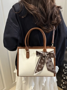 White snake pattern tote bag with brown handles and a stylish heart bow ribbon decoration