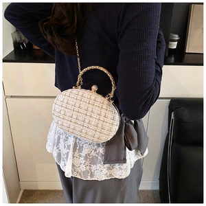 Dettaglio della chiusura con perle e strass su borsa a tracolla in tweed bianco e oro