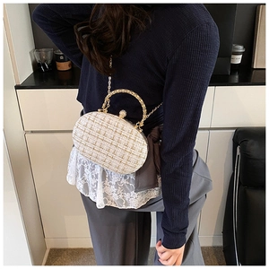 Detail of white and gold tweed clutch bag with woven metal handle and chain strap