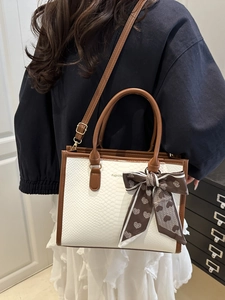 White snake pattern handbag with brown leather trim and decorative ribbon bow accessory