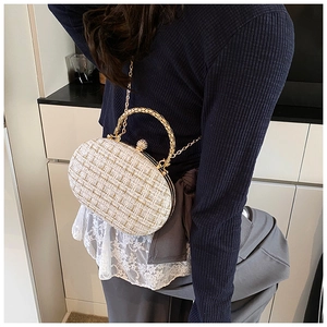 Detail of tweed evening clutch with golden metal handle and ball-lock closure