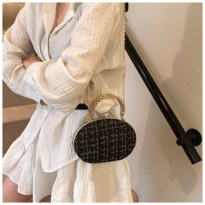 Dettaglio borsa da sera in tweed nero con catena d'oro e manico intrecciato sul modello