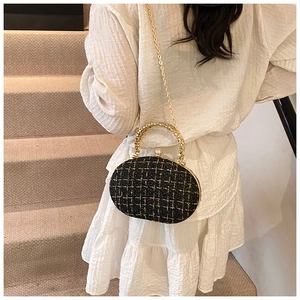Detail of tweed check pattern party clutch bag with golden ring handle and chain strap