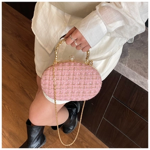 Detail of pink woven clutch bag featuring a gold metal handle and a rhinestone ball clasp