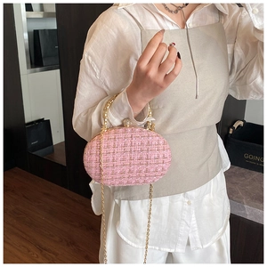Detail showing pink tweed texture with pearl clasp and golden handle on the evening bag