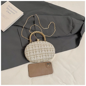 Detail of tweed fabric texture and gold metal handle on a luxury oval evening clutch bag