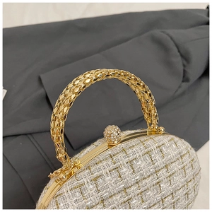 Detail of white tweed texture and gold metal handle with crystal ball clasp of small square bag
