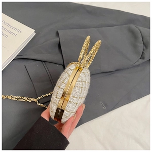 Detail of woven evening bag with gold rabbit ear handles and sparkling metallic fibers