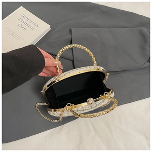 Detail of tweed evening bag showing gold frame, metal handles, and crystal clasp