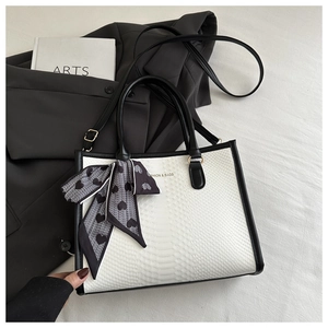 Detail view of monochrome snakeskin tote with fashion logo and decorative heart scarf