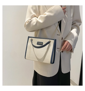 Détail du cabas en toile contrastée avec lettrage doré 'FASHION' et bandoulière chaîne