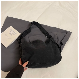 Détail du sac bandoulière en denim noir délavé avec sangle et rivets métalliques
