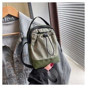 Detail of green nylon crossbody bag showing the drawstring closure and adjustable strap