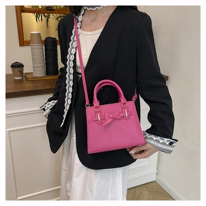 Sac à main carré rose avec nœud décoratif présenté dans un cadre décontracté