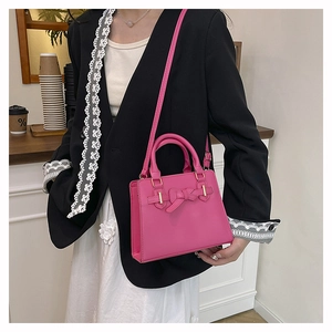 Sac à main fuchsia avec nœud porté par un mannequin, style élégant et détails dorés fins