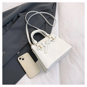 Détail d'un sac à main blanc en cuir avec nœud décoratif et boucles en métal doré