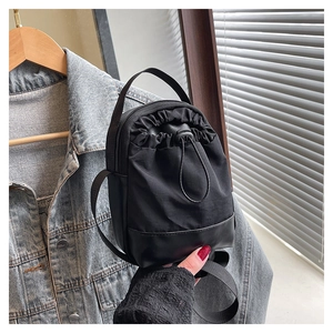 Detail of black nylon drawstring crossbody bag with adjustable strap and carry handle
