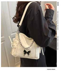 Detail of cream white shoulder bag with black butterfly buckle and silver chunky chain strap