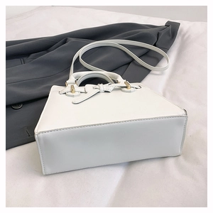 Détail du sac à main trapèze blanc avec nœud en cuir et fermoir en métal doré