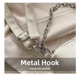 Detail of silver hardware hook and chain on cream leather crossbody bag for women