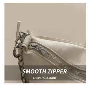 Detailed close-up of smooth silver zipper and stitching on cream leather shoulder bag