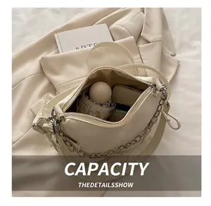 Interior view showing capacity for a cream-white crossbody bag with chain detail