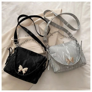 Detail of elegant shoulder bag featuring a metallic butterfly buckle and pleated texture