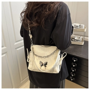 Détail du sac bandoulière blanc à motif papillon avec chaîne argentée sur modèle