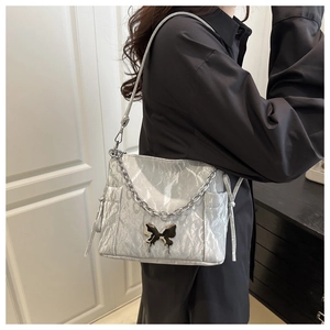 Detail of silver pleated shoulder bag with large metal butterfly and chain strap